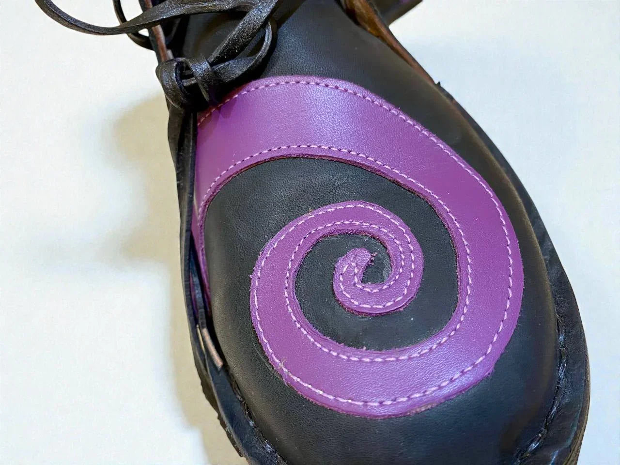 Black medieval leather boot with purple spiral design, handmade full-grain leather, detailed stitching and wrap laces