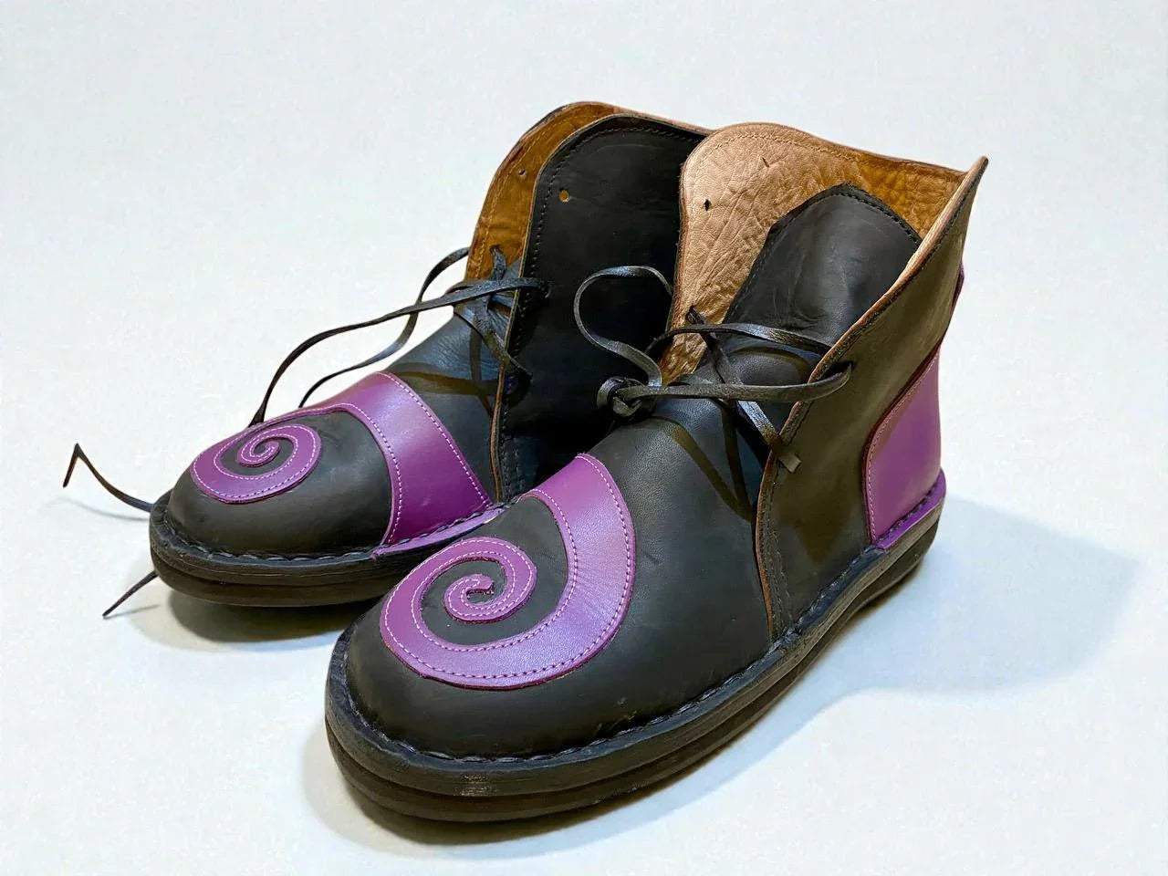 Handmade medieval leather boots with purple swirl accents, wrap laces, and full-grain leather texture for LARP or Renaissance faire.