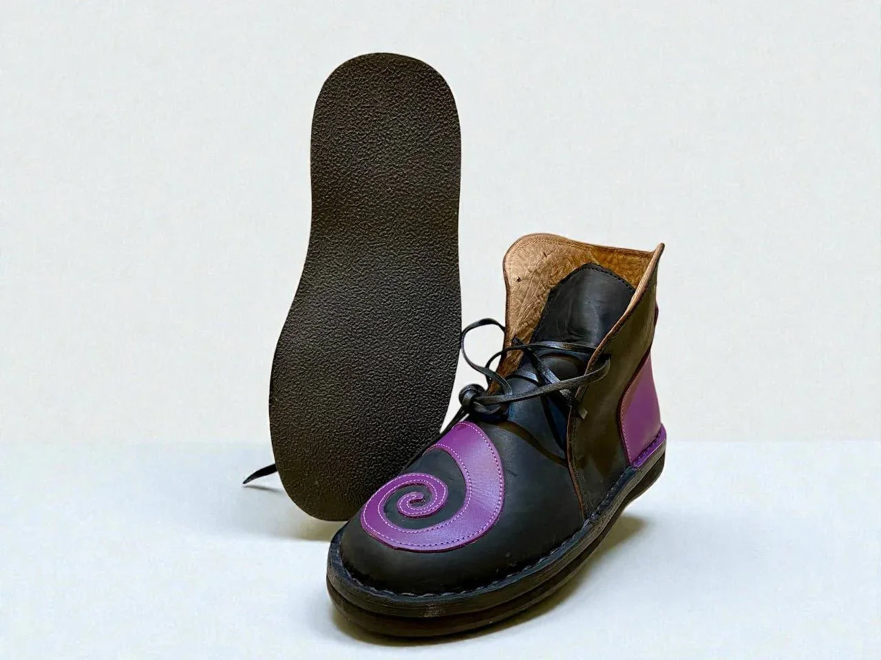Black and purple handmade leather boot with spiral design, wrap laces, and full-grain leather sole for LARP or Renaissance faire.