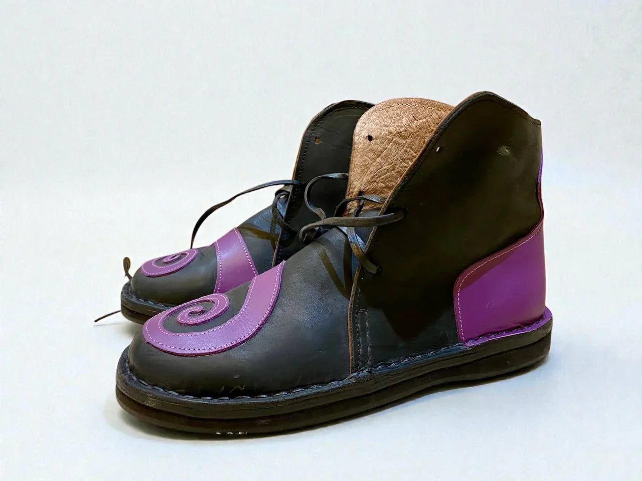 Handmade medieval leather boots with purple swirl accents, wrap laces, and full-grain leather texture for LARP or Renaissance faire.