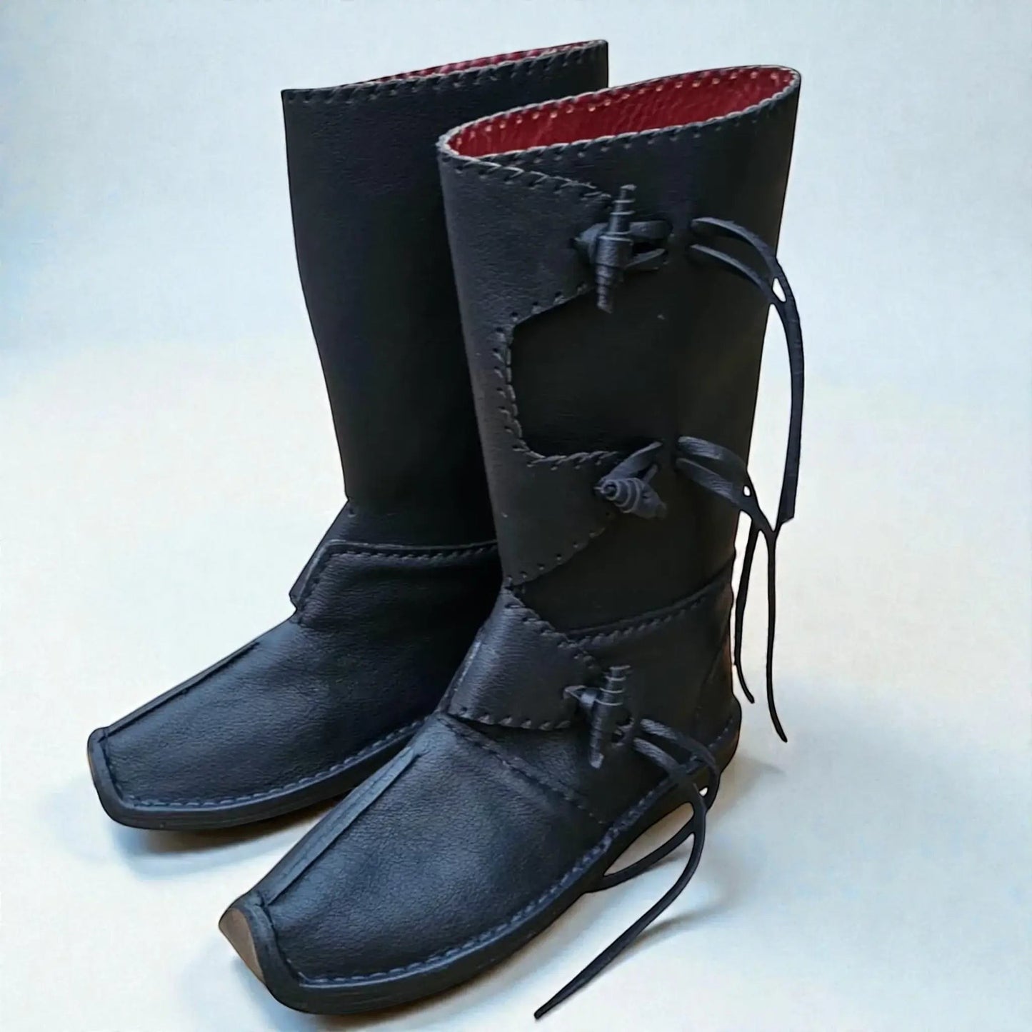 Handmade black medieval leather boots with wrap laces, red lining, and visible stitching for LARP or SCA reenactment.
