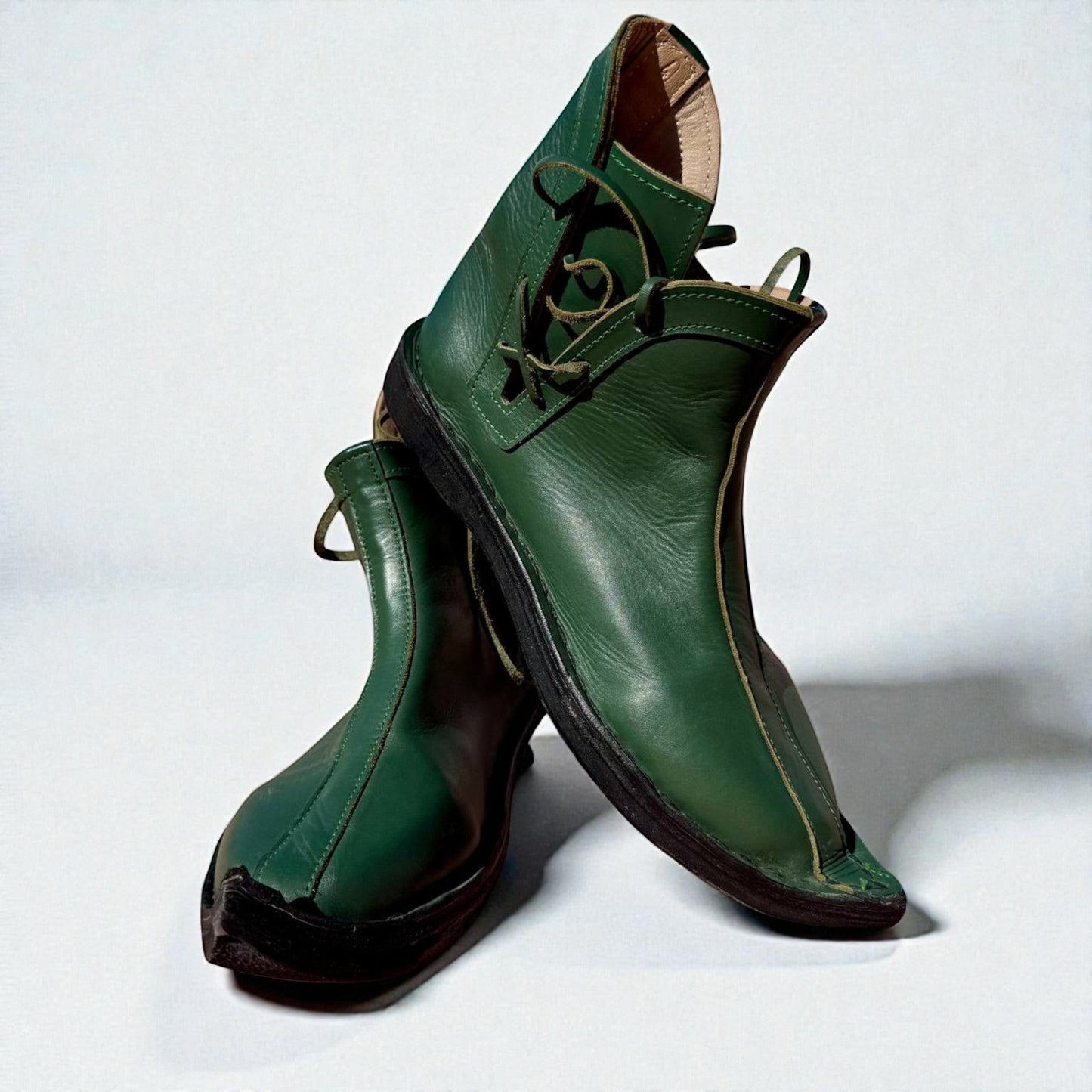 Handmade green medieval leather boots with wrap laces, visible stitching, and full-grain texture, ideal for LARP or SCA reenactment.