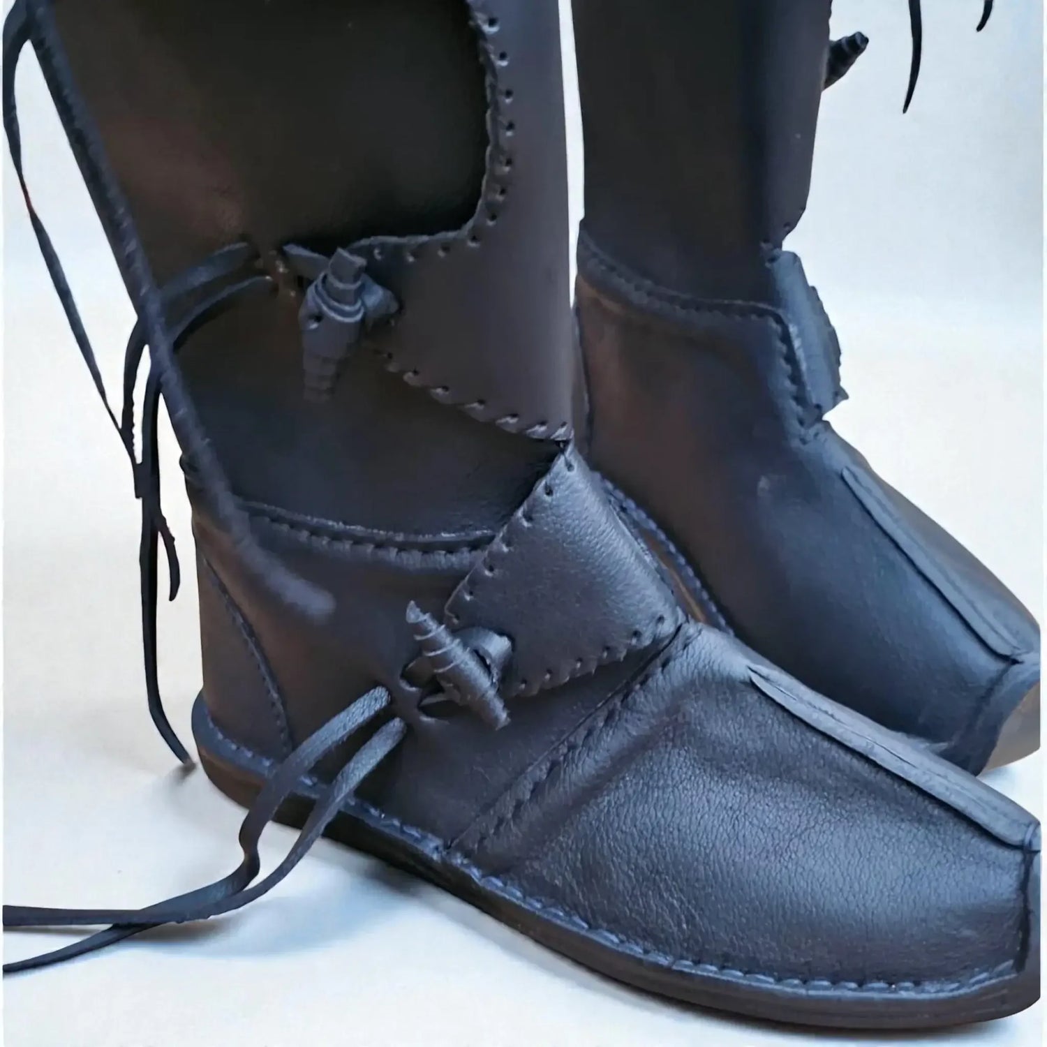 Black handmade medieval leather boots with wrap laces and visible stitching, crafted from full-grain leather for LARP or SCA.