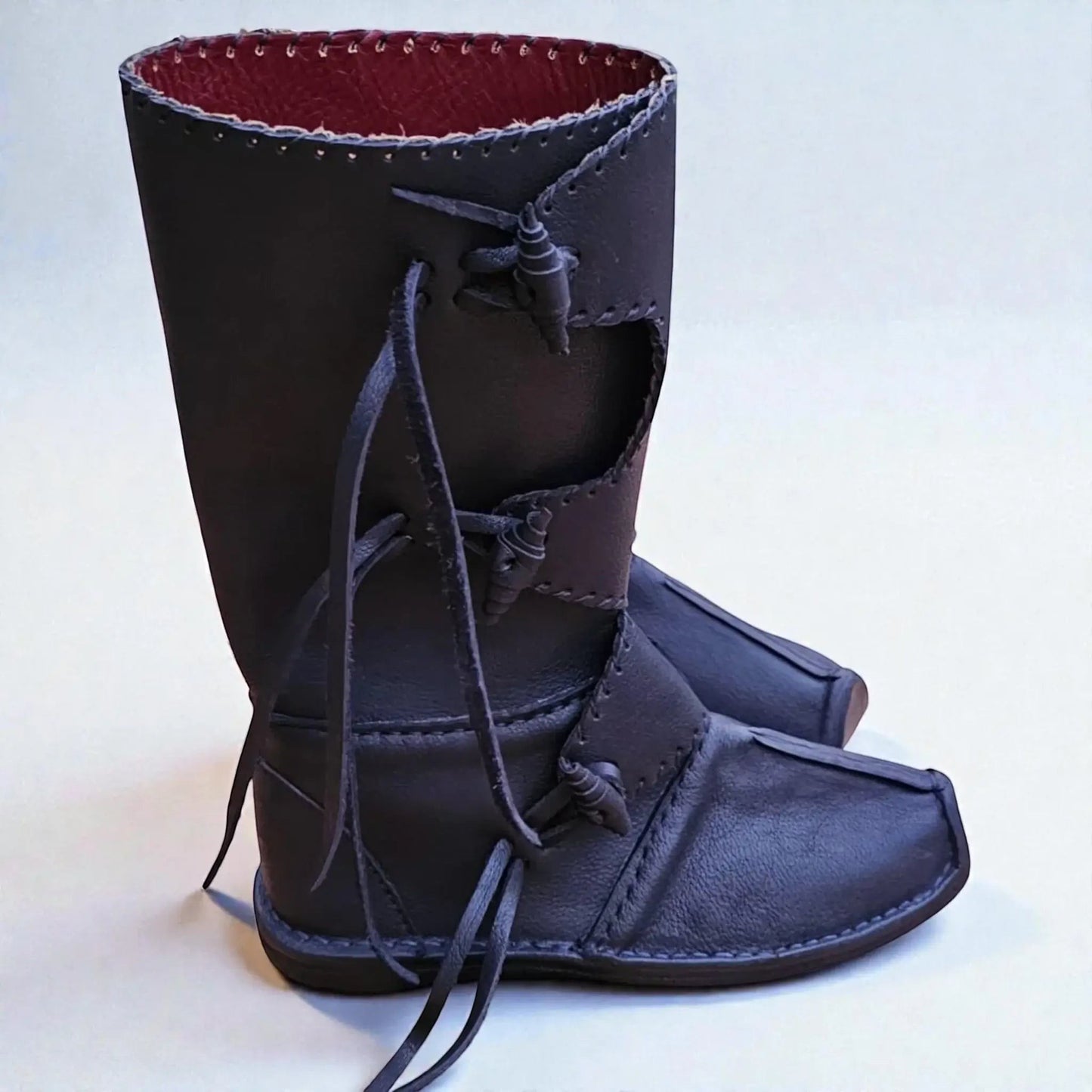 Handmade black medieval leather boots with wrap laces, red lining, and visible stitching for LARP or SCA reenactment.