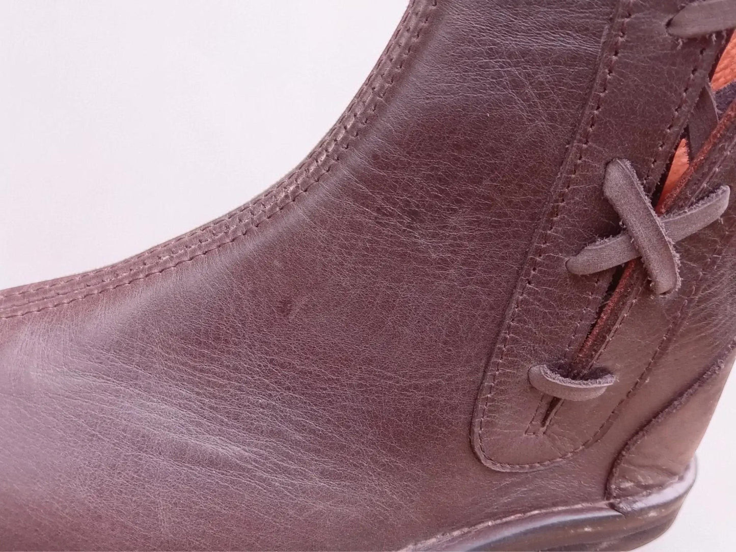 Close-up of handmade medieval leather boot with full-grain texture, wrap laces, and detailed stitching.