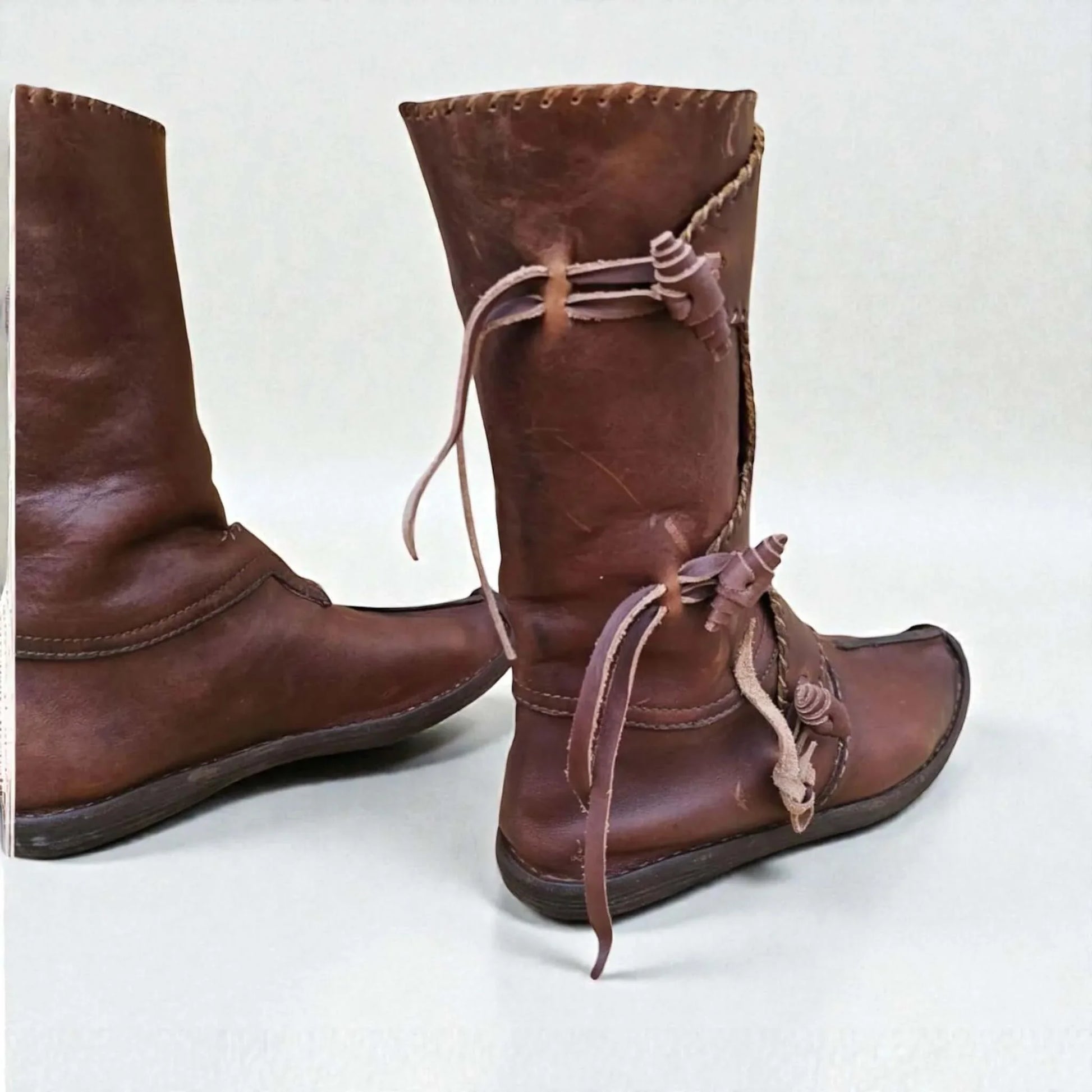 Handmade medieval leather boots with wrap laces and visible stitching, crafted from full-grain leather for LARP or SCA reenactment.