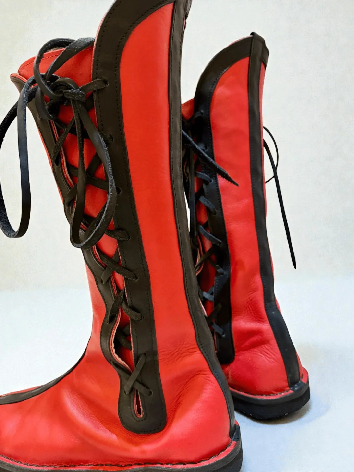 Vibrant red and black handmade leather boots with wrap laces, ideal for LARP or Renaissance faire events.