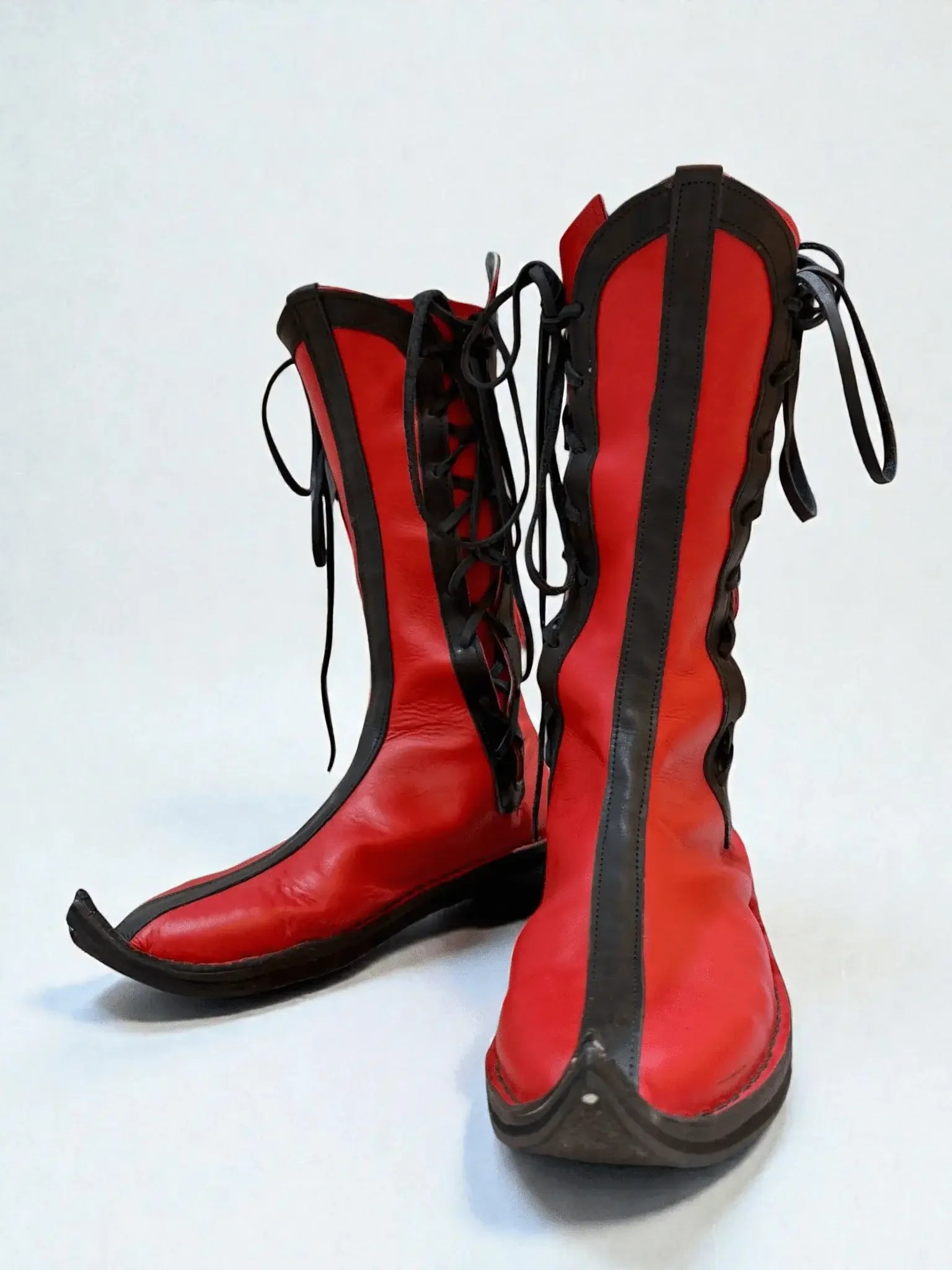 Vibrant red medieval leather boots with black laces and pointed toes, crafted for LARP or Renaissance faire wear.