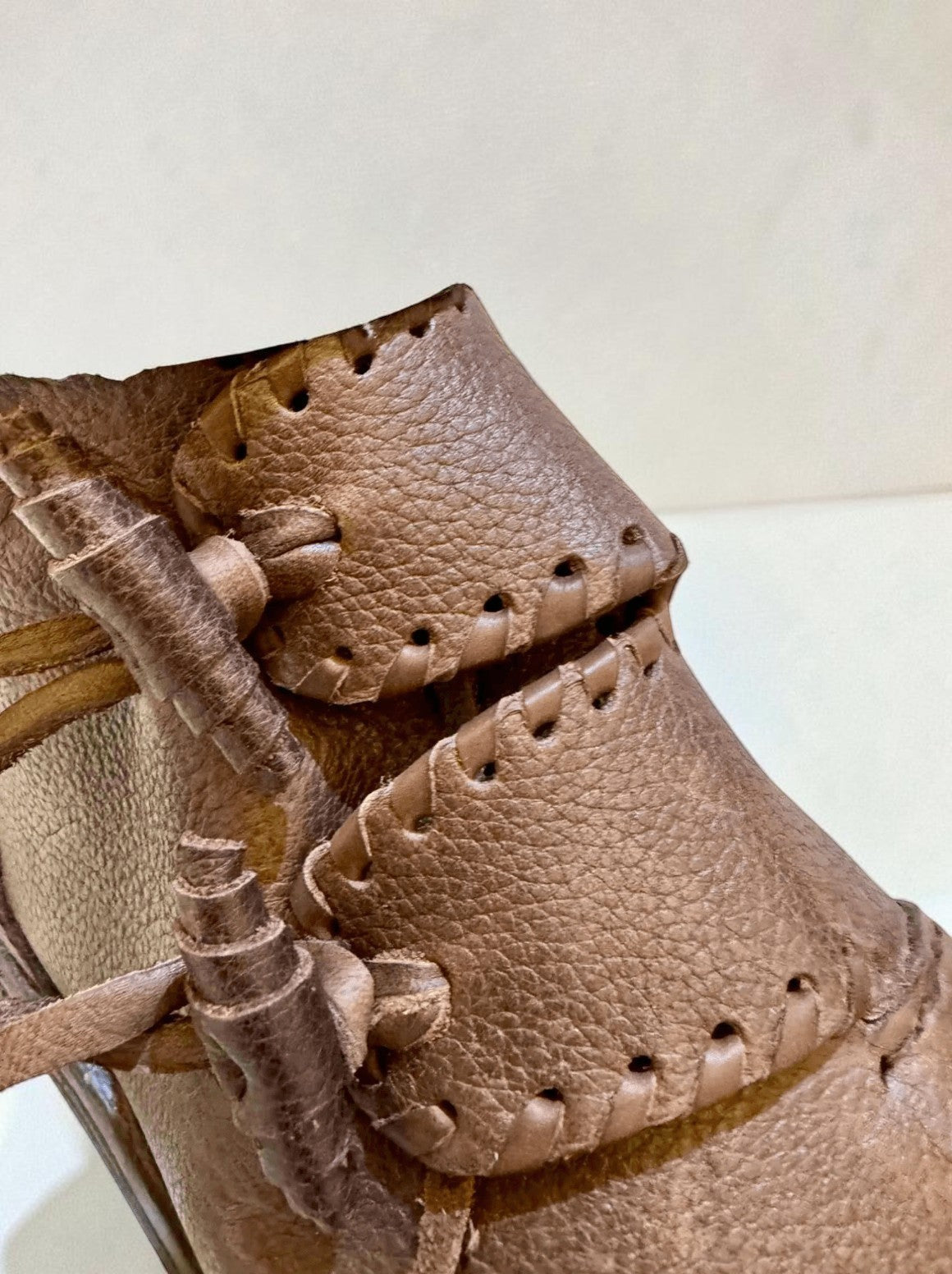 Close-up of handmade medieval leather boots with wrap laces and visible stitching on full-grain leather