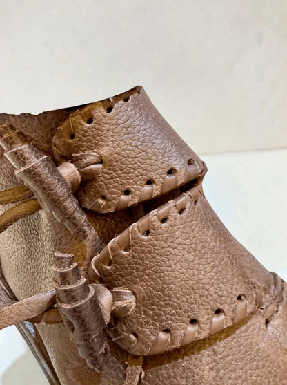 Close-up of handmade medieval leather boots with wrap laces and visible stitching on full-grain leather
