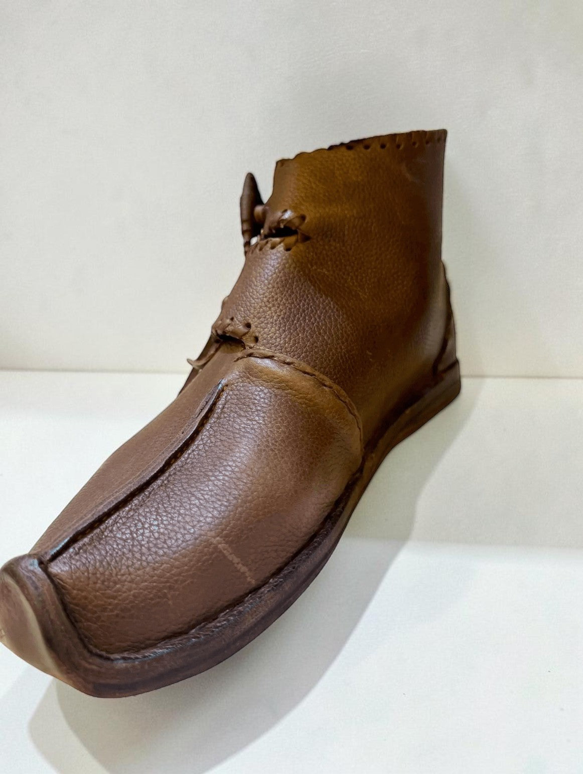 Handmade brown medieval leather boot with wrap laces and visible stitching, crafted from full-grain leather.