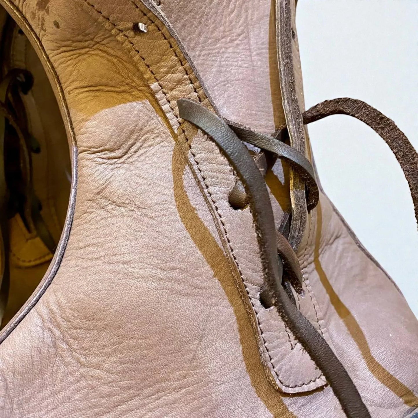 Close-up of handmade medieval leather boots showing full-grain texture, wrap laces, and detailed stitching.