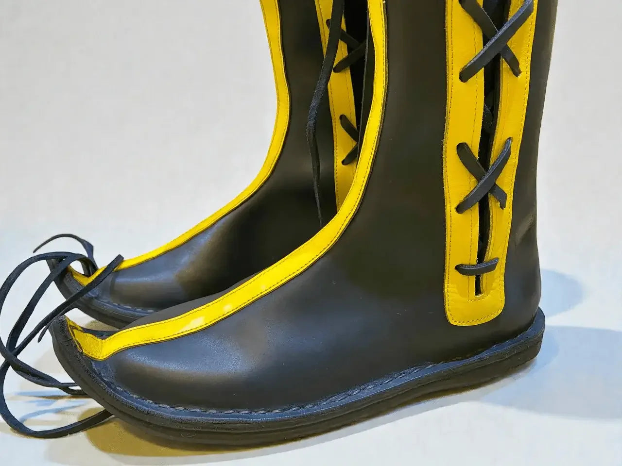 Black and yellow handmade medieval leather boots with wrap laces and full-grain leather texture, ideal for LARP or Renaissance faire.