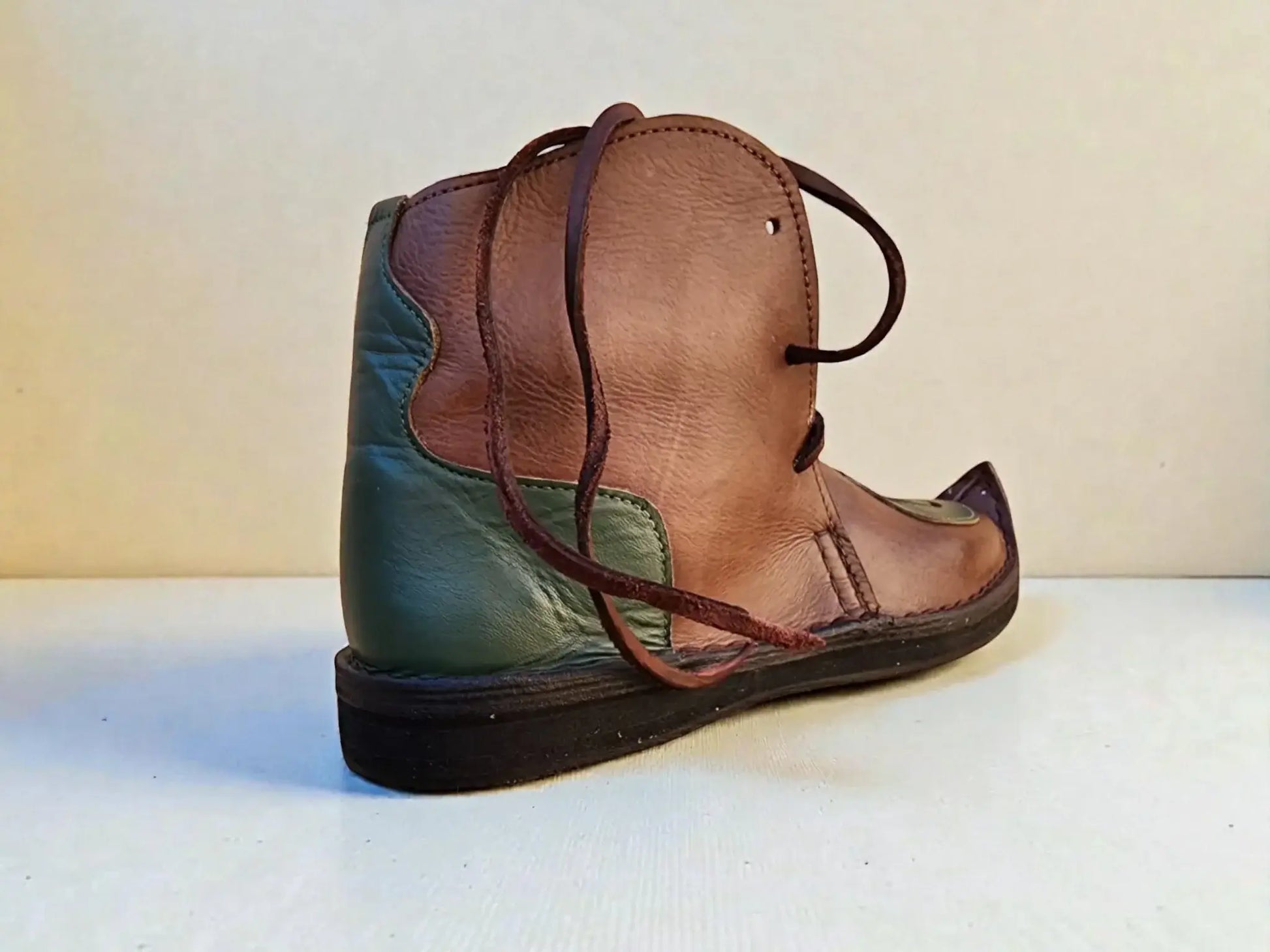 Handmade medieval leather boot with wrap laces, full-grain texture, and green-brown panels for LARP or SCA reenactment.