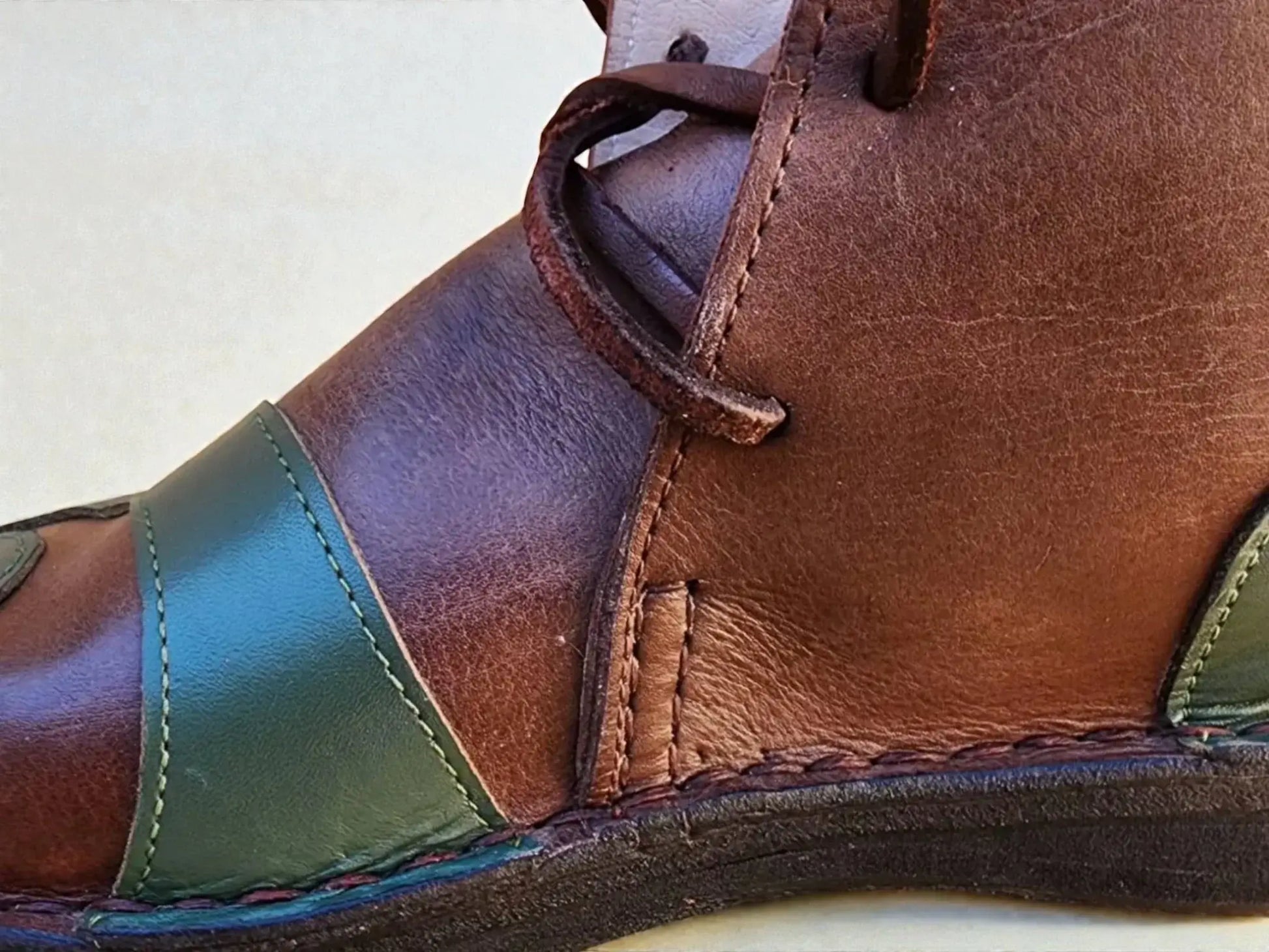 Handmade medieval leather boot with rich brown and green full-grain leather, detailed stitching, and wrap laces for LARP or SCA.