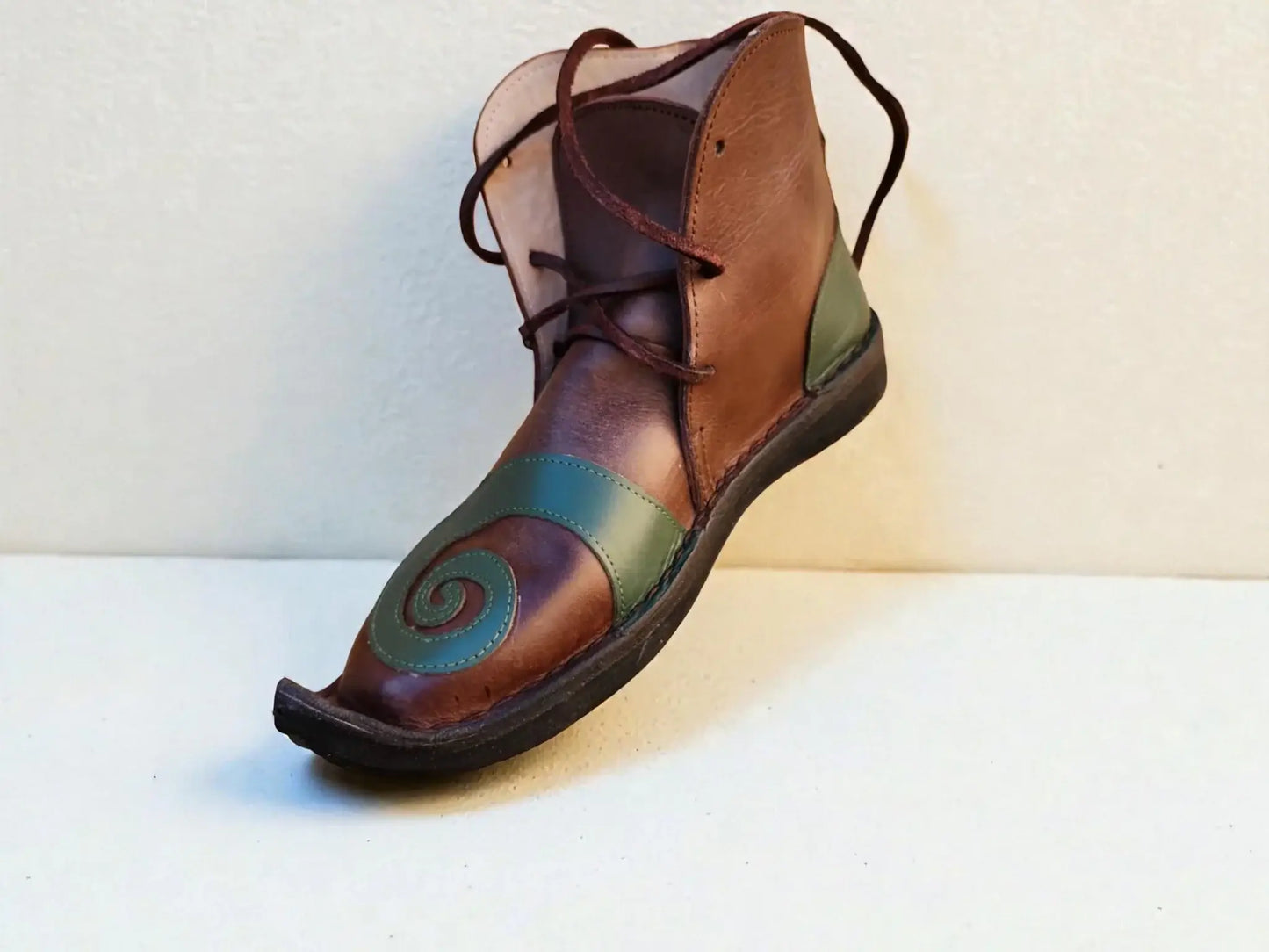 Handmade medieval leather boot with green spiral design, wrap laces, and full-grain texture for LARP or Renaissance faire