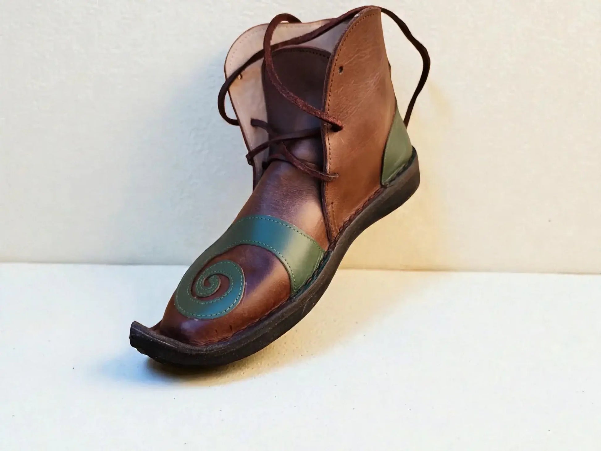 Handmade medieval leather boot with green spiral design, wrap laces, and full-grain texture for LARP or Renaissance faire