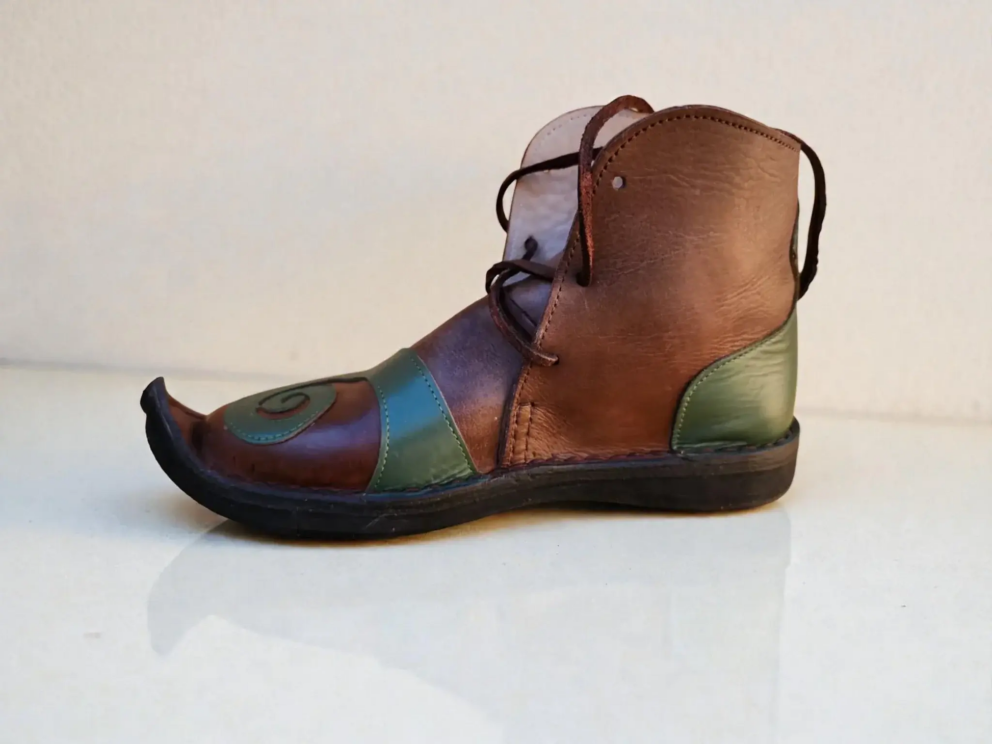 Handmade medieval leather boot with pointed toe, wrap laces, and green-brown full-grain leather panels for Renaissance faire or LARP.