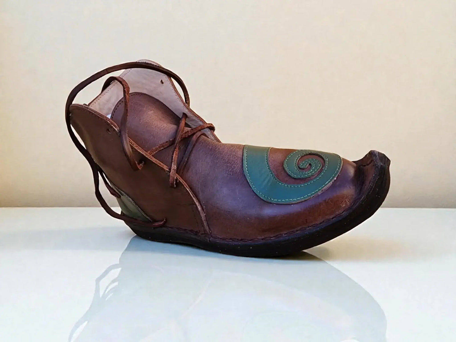 Handmade medieval leather boot with green spiral design, wrap laces, and full-grain texture for LARP or Renaissance faire.