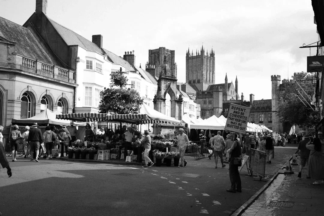 Medieval market scene with historic architecture, street vendors, and pedestrians — ideal for Renaissance faire or SCA reenactment footwear.