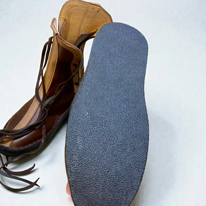 Handmade medieval leather boot with wrap laces and textured sole, showcasing full-grain leather craftsmanship.